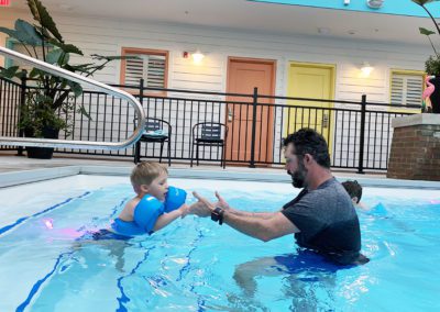Father helping son enter swimming pool